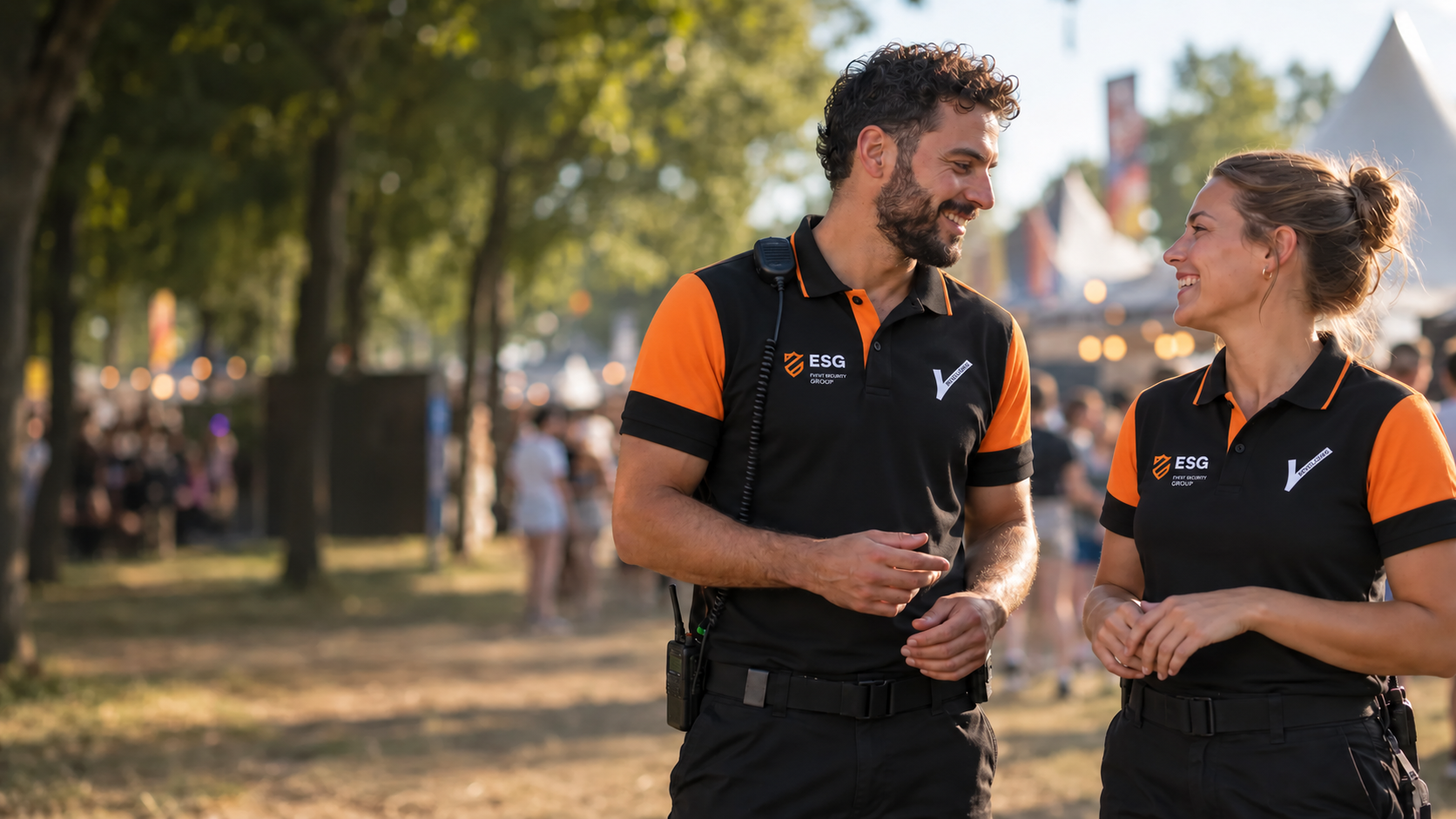 Twee lachende beveiligers in zwart-oranje ESG-polo’s op een festival